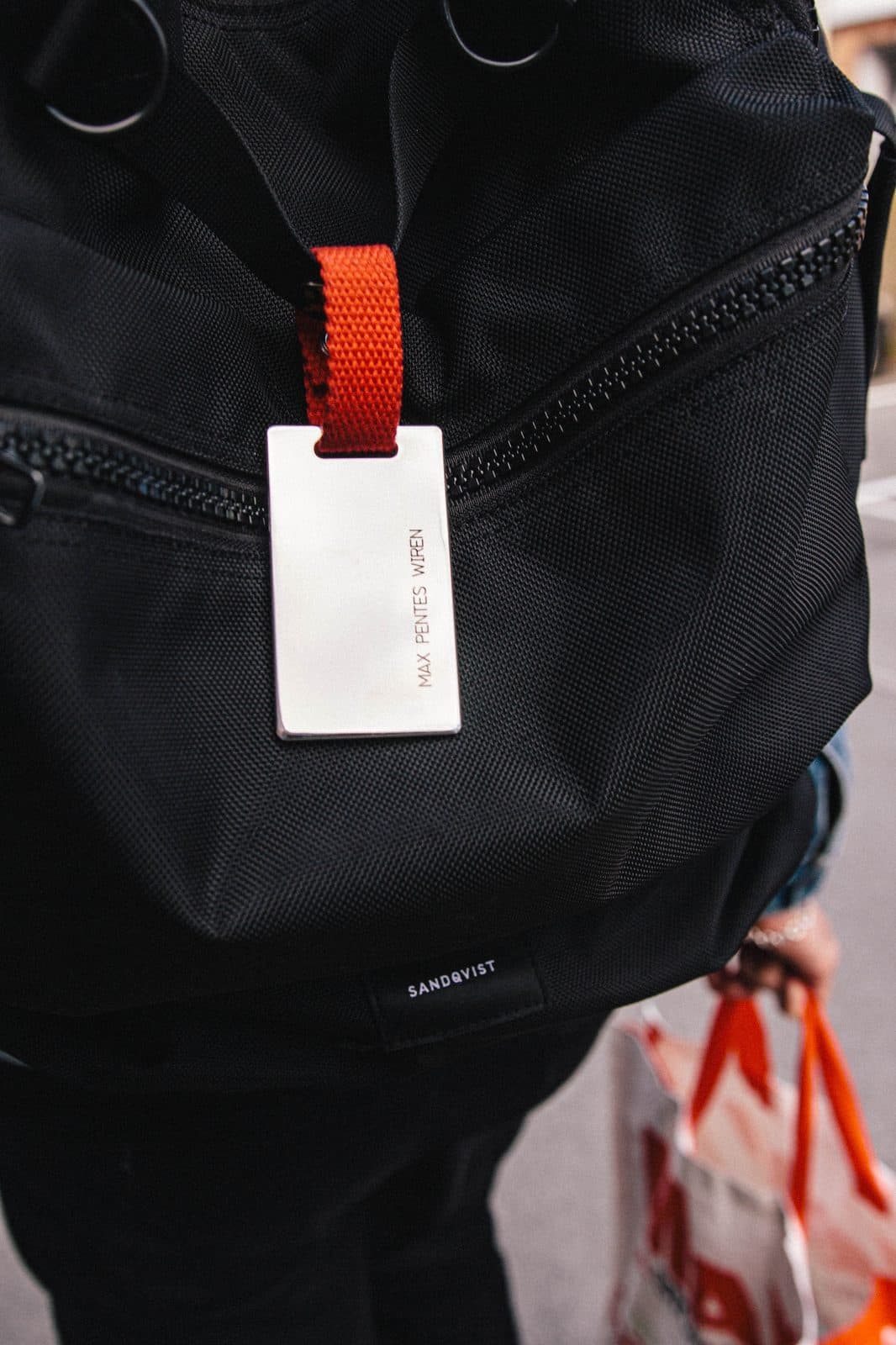 Luggage tag attached to a backpack — in use